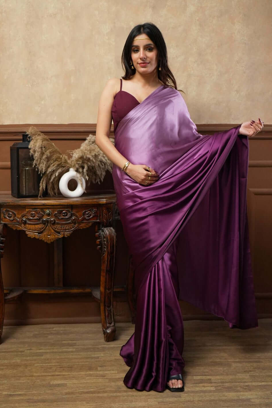 A woman models Viola Burgundy Glass Shine Satin Saree