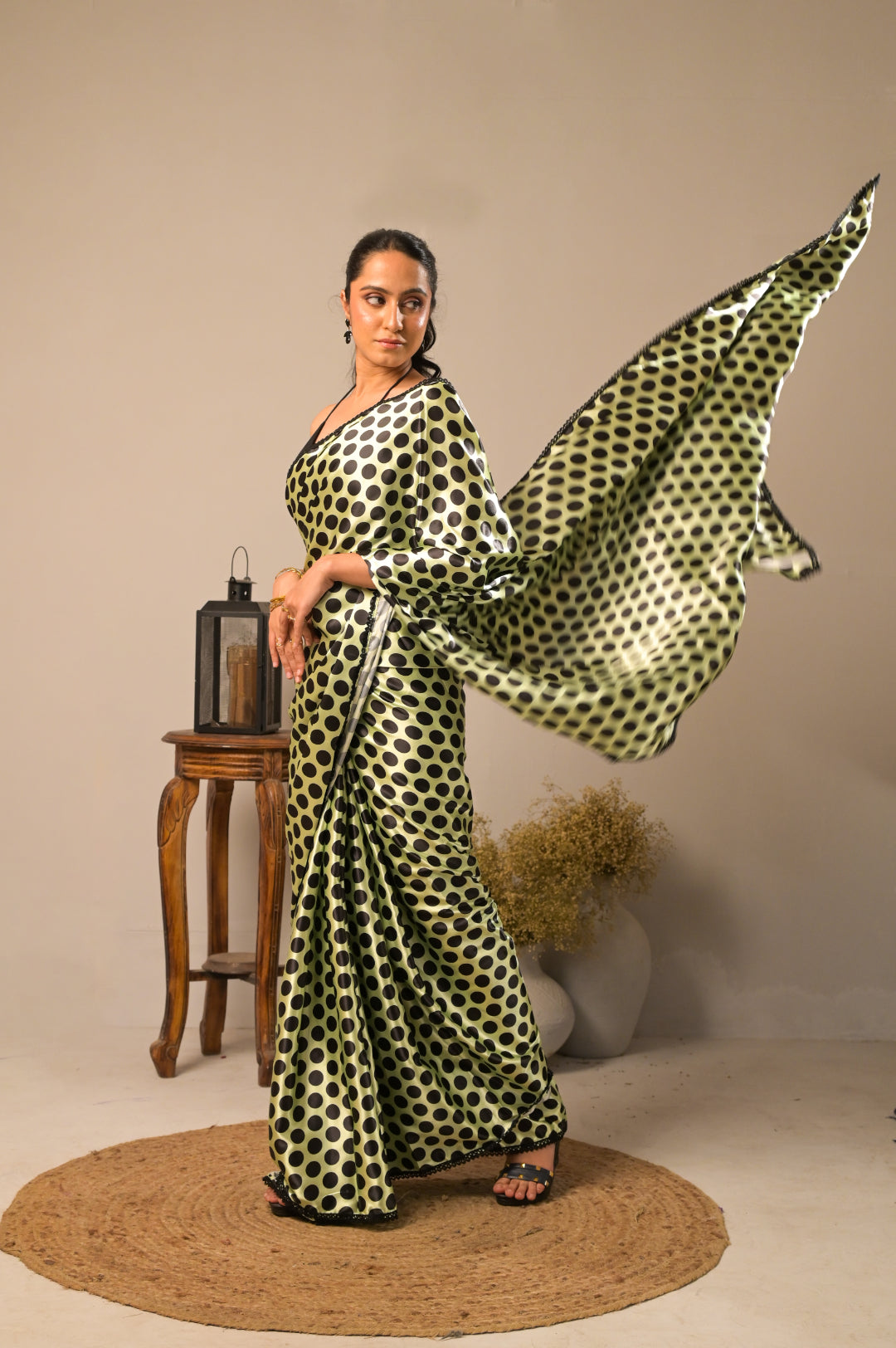 Model showcasing the Kiwi Dots Satin Polka Dot Saree with flowing fabric and polka dot design.